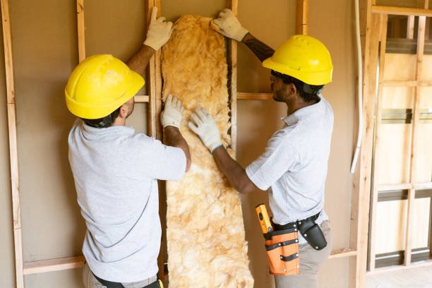 Construction workers fitting insulation in frame